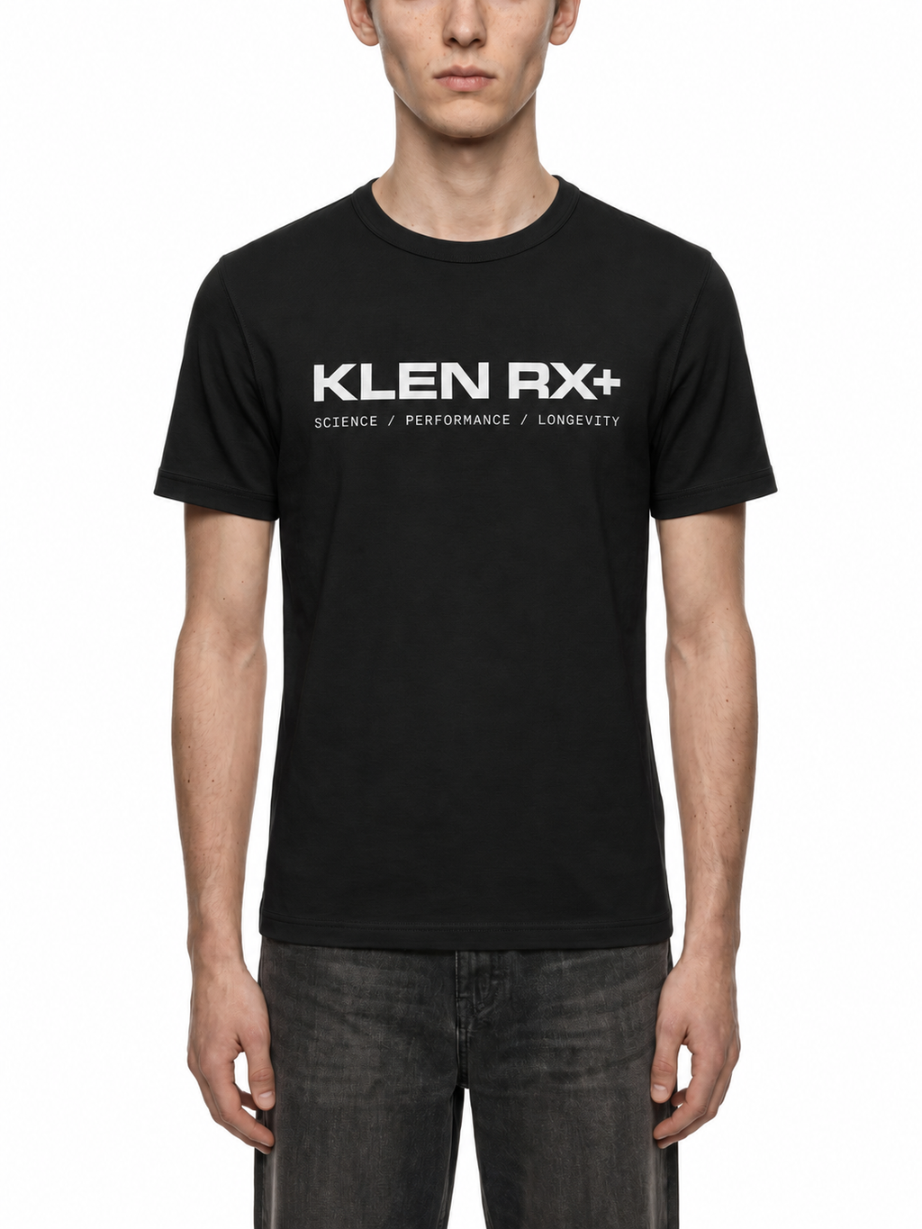 A man wearing a black short-sleeve crewneck t-shirt with 'KLEN RX+' printed in white across the chest, paired with dark gray jeans, against a plain white background.