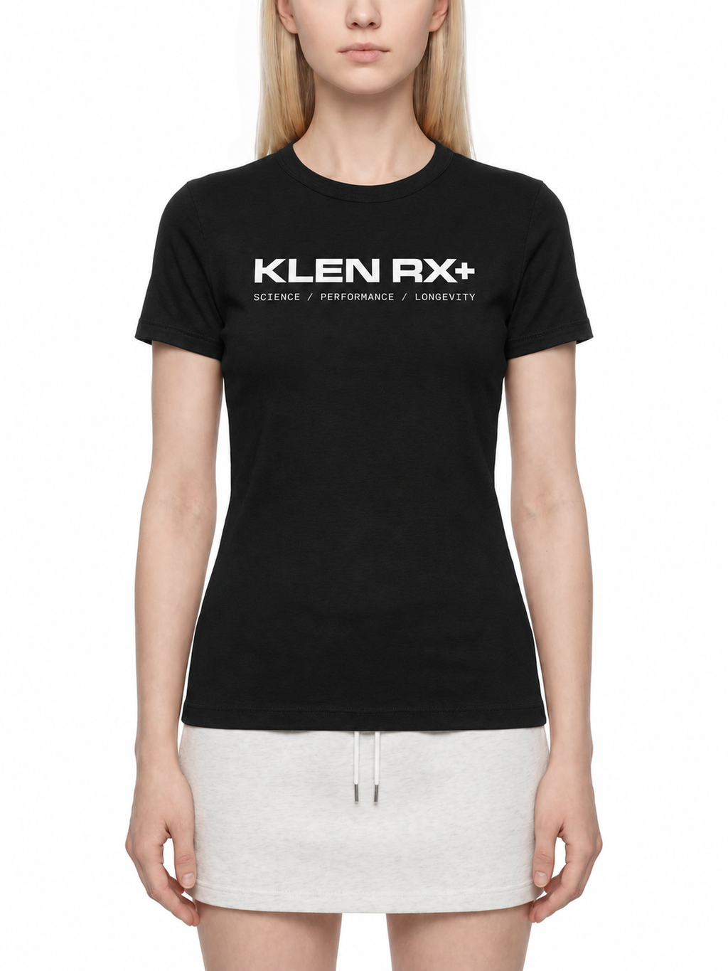 A woman wearing a fitted black short-sleeve T-shirt with white 'KLEN RX+' text across the chest, paired with a light gray mini skirt, against a plain white studio background.